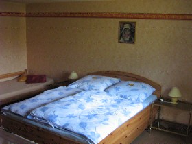 Schlafzimmer mit Doppelbett, Einzelbett und Kinderbett. (Links des Bildausschnittes) 